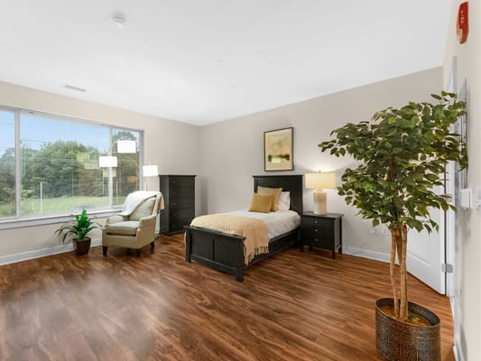 A well-furnished resident room with a bed and chair