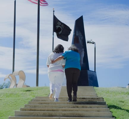 Two women walking up stairs towards a memorial.