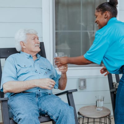 Staff member serving a drink to a resident on the porch