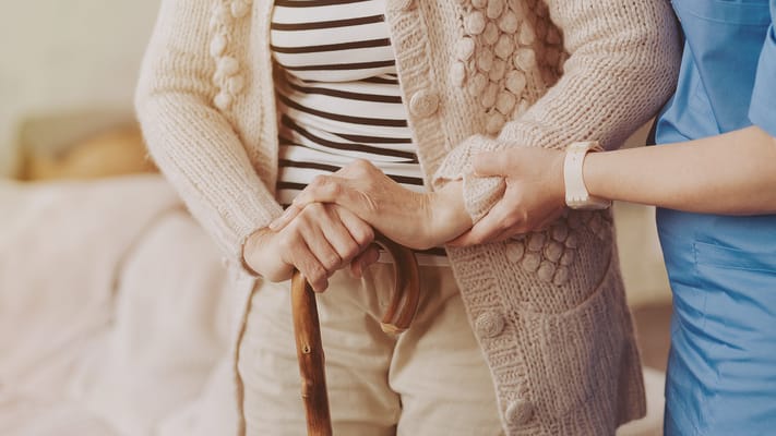 Caregiver assisting a resident with a cane