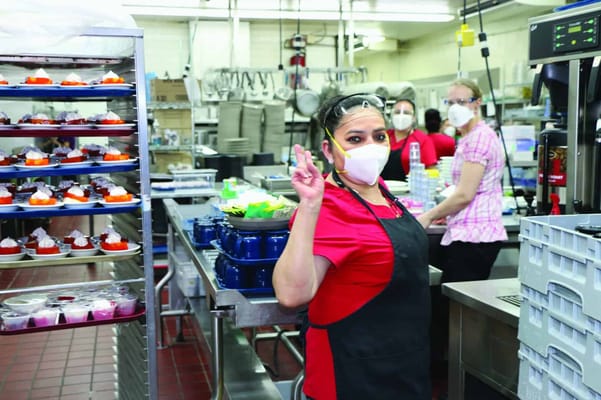 Staff member in kitchen preparing food with safety gear