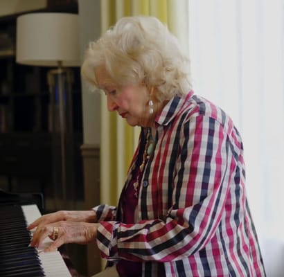 Senior woman playing piano in a bright room