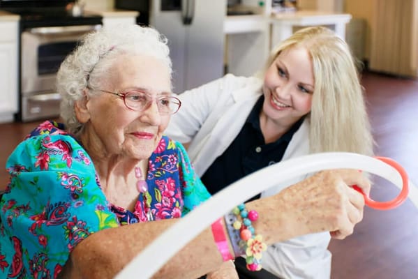 Caregiver assisting a smiling senior with an activity