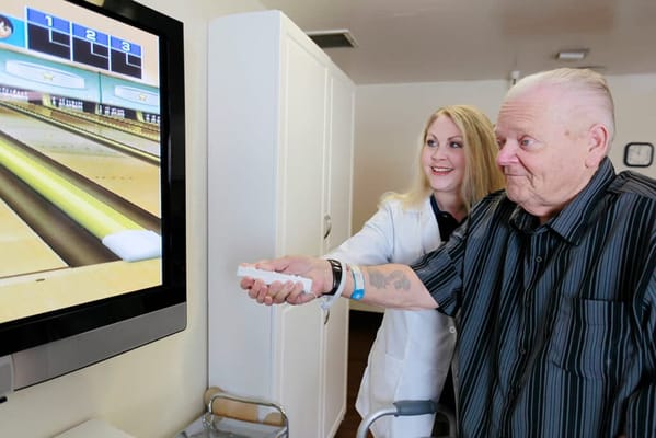 Resident engaging in a virtual bowling game with staff