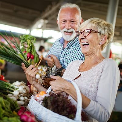 Seniors smiling and enjoying fresh produce at a market