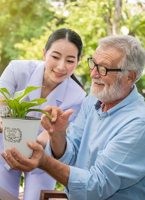 A caregiver and a resident interacting with a plant