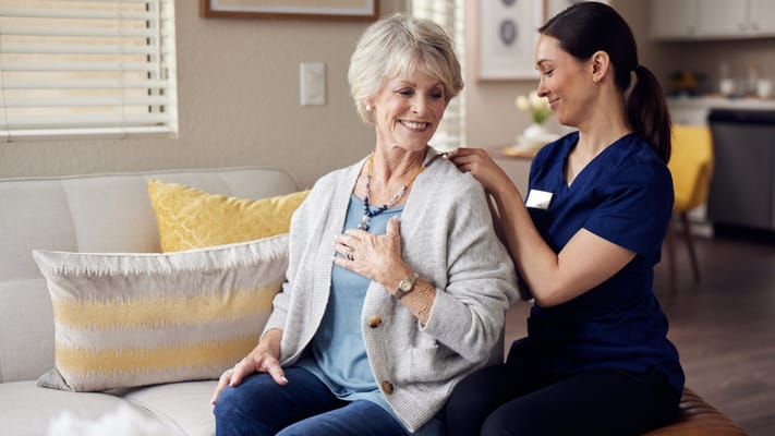 A caregiver assisting a senior woman in a cozy interior