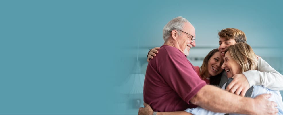 Family members hugging a senior man in a warm setting