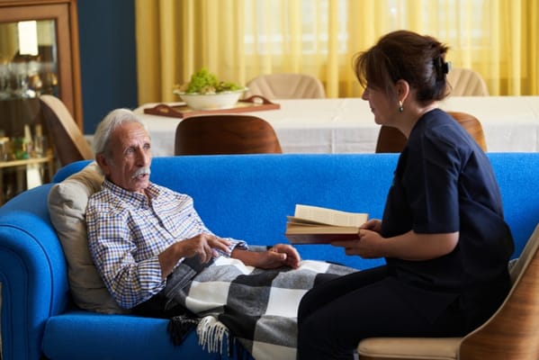 Caregiver reading to resident in a cozy lounge