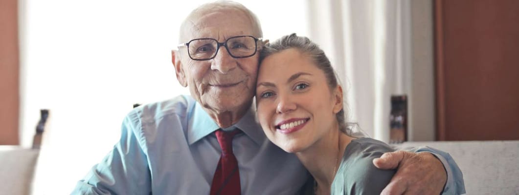 An elderly man and a young woman smiling together