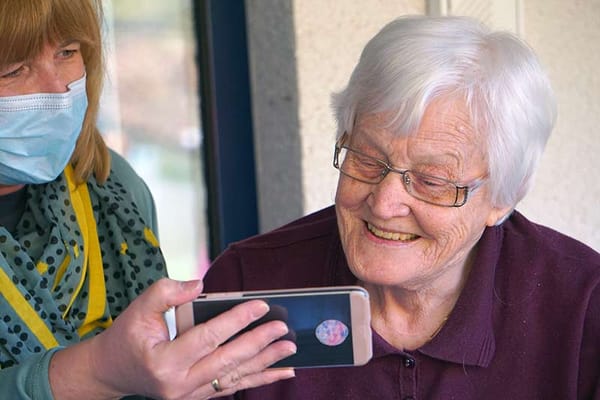 Staff member showing a smartphone to a smiling resident