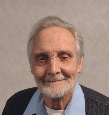 Smiling elderly man with gray hair in a blue collared shirt