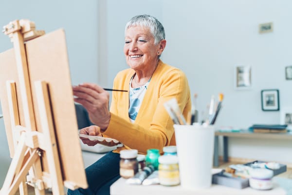 Senior woman painting in a bright activity room