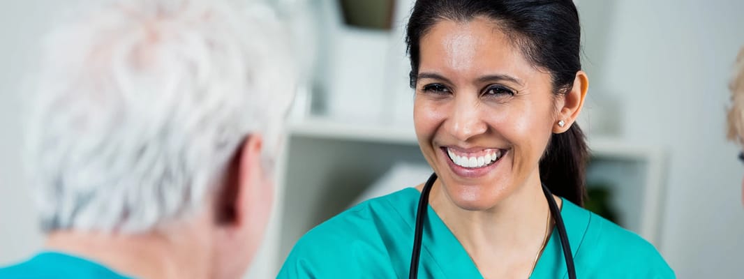 A caregiver smiles while talking to a resident