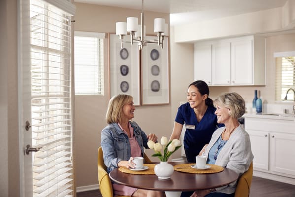 Residents enjoying tea with staff in a cozy room