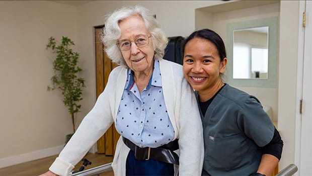 A smiling resident with a staff member in a care facility