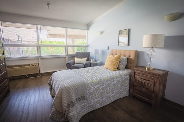 A cozy furnished resident room with natural light