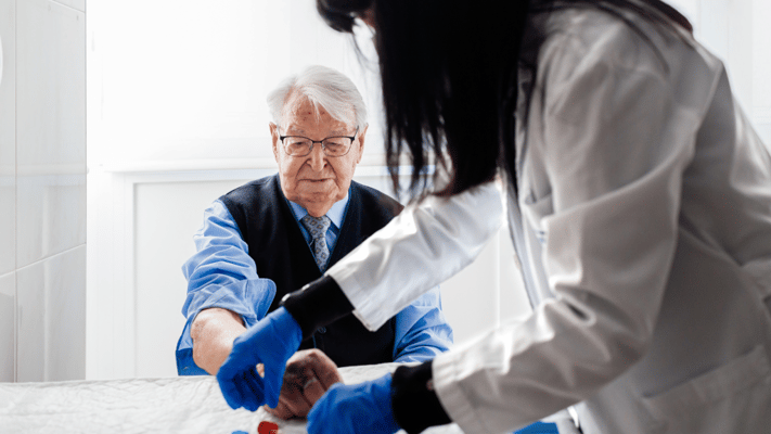 A caregiver assisting a senior man in a facility.