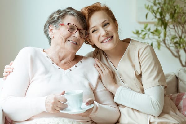 A caregiver and resident smiling together indoors