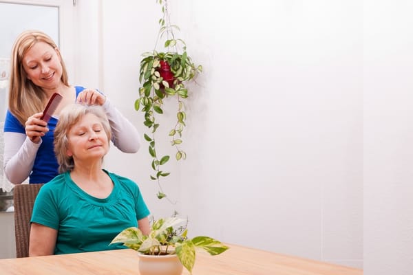 Caregiver styling hair of a resident in a warm setting