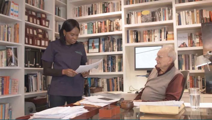 Caregiver assisting a senior resident in an office setting