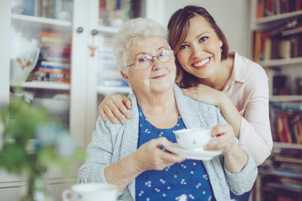 Smiling elderly woman holding a teacup with aide