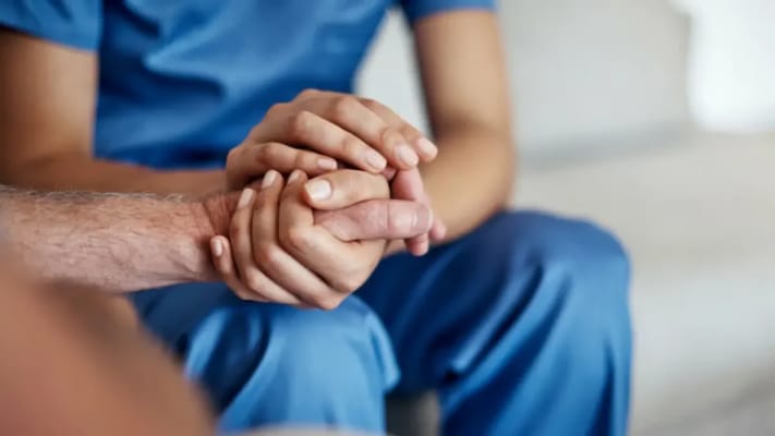 Close-up of resident and staff hands together