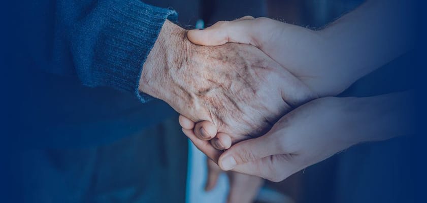 A caregiver holding the hand of a senior resident