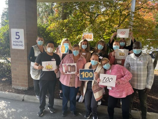 Staff celebrating with signs outdoors at the facility.