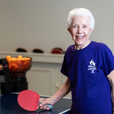 Senior resident playing ping pong with a smile