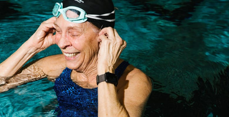 Elderly woman swimming in a pool, smiling