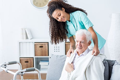 Nurse assisting an elderly man in a cozy living area