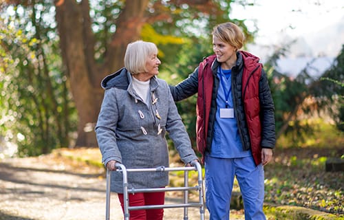 A staff member assisting a senior resident outdoors