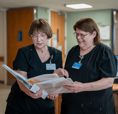 Two staff members reviewing a document in an interior setting