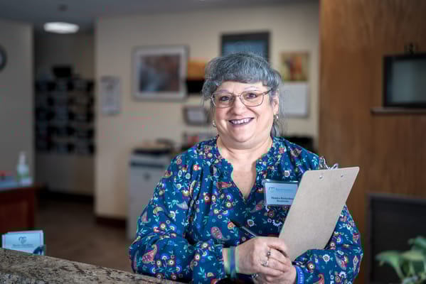 Staff member smiling at reception with a clipboard