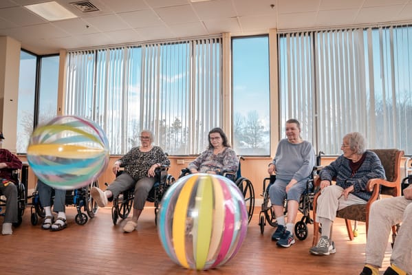 Residents playing with colorful beach balls in an activity room