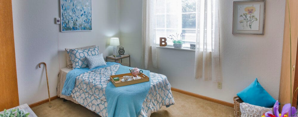 A well-decorated private resident room with a bed and artwork