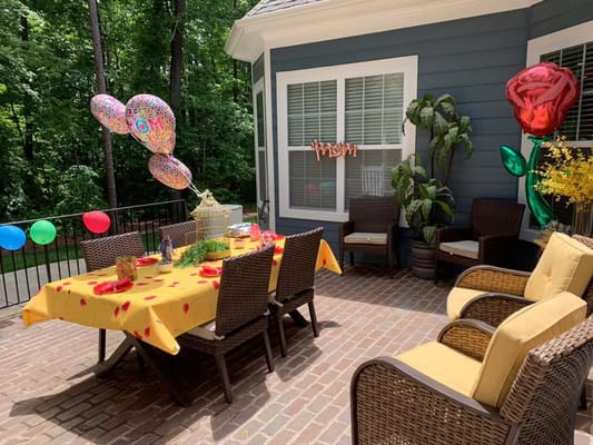 Outdoor patio decorated for a celebration with balloons and a table set up.