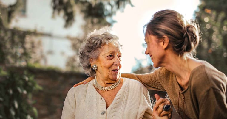 A resident enjoying time with a caregiver in a garden setting.
