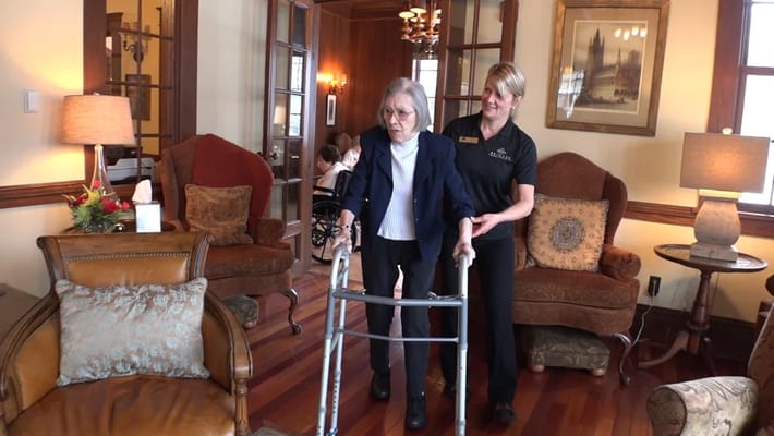 Staff assisting a resident with a walker in a cozy interior