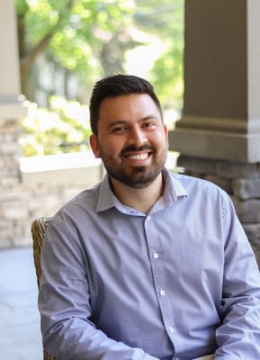 A staff member smiling on a porch in a garden setting