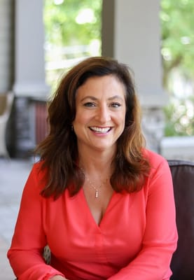 A smiling woman in a coral blouse outdoors