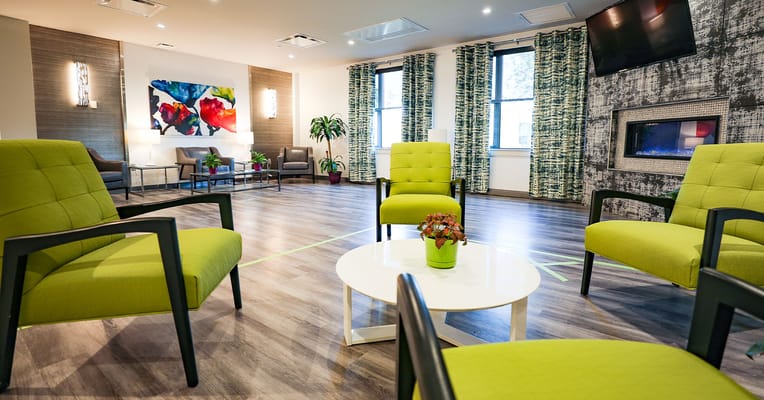 Bright common area with green chairs and artwork