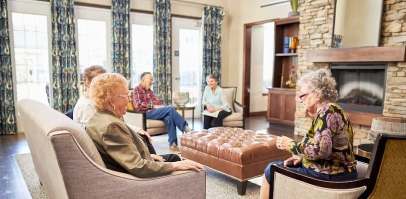 Seniors sitting together in a comfortable living room, engaging in conversation.