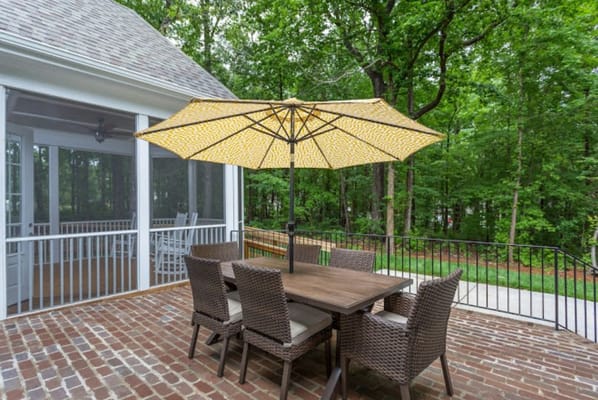 Outdoor dining area with table and umbrella in a green setting