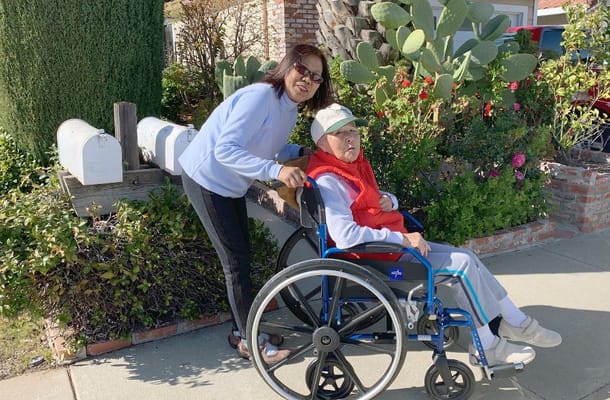 Resident in a wheelchair with staff member outdoors