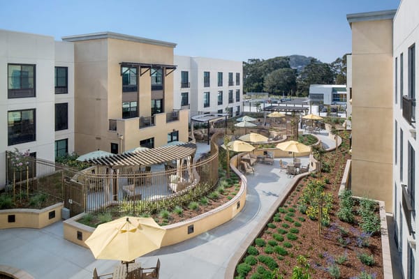 Outdoor garden area with seating and umbrellas at Belmont Village Senior Living Albany