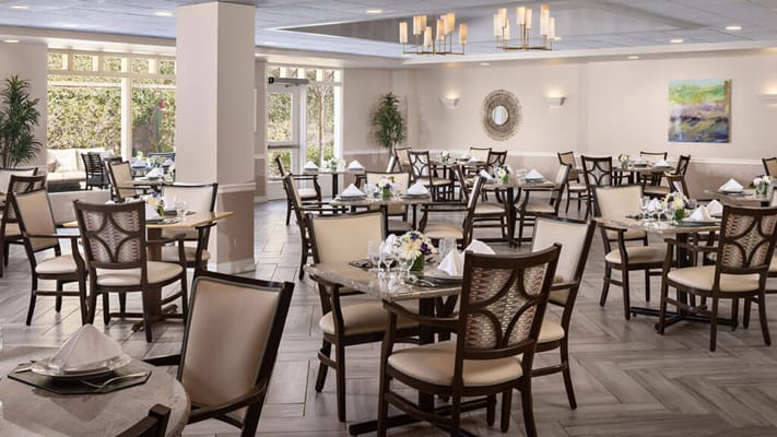 Dining room with tables set for guests at Belmont Village Senior Living