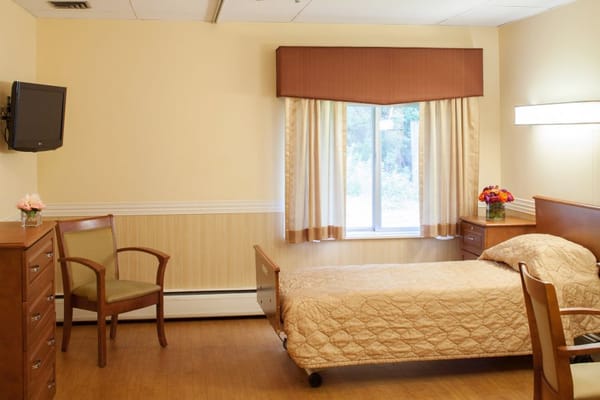 A comfortable bedroom with a bed, chair, and dresser.