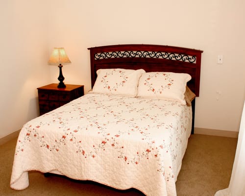 A cozy bedroom with a floral quilt and lamp